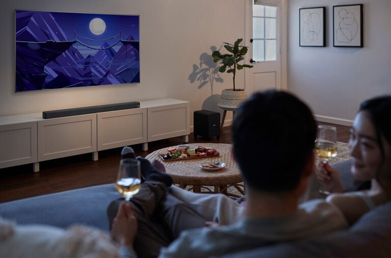 A couple watching TV and drinking wine.