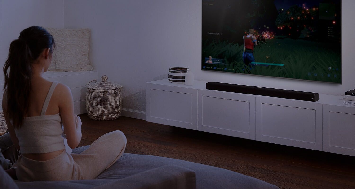 a couple watching TV with a large sound bar sitting under it.