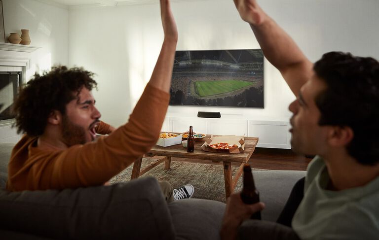 Two men high fiving, watching a football game.