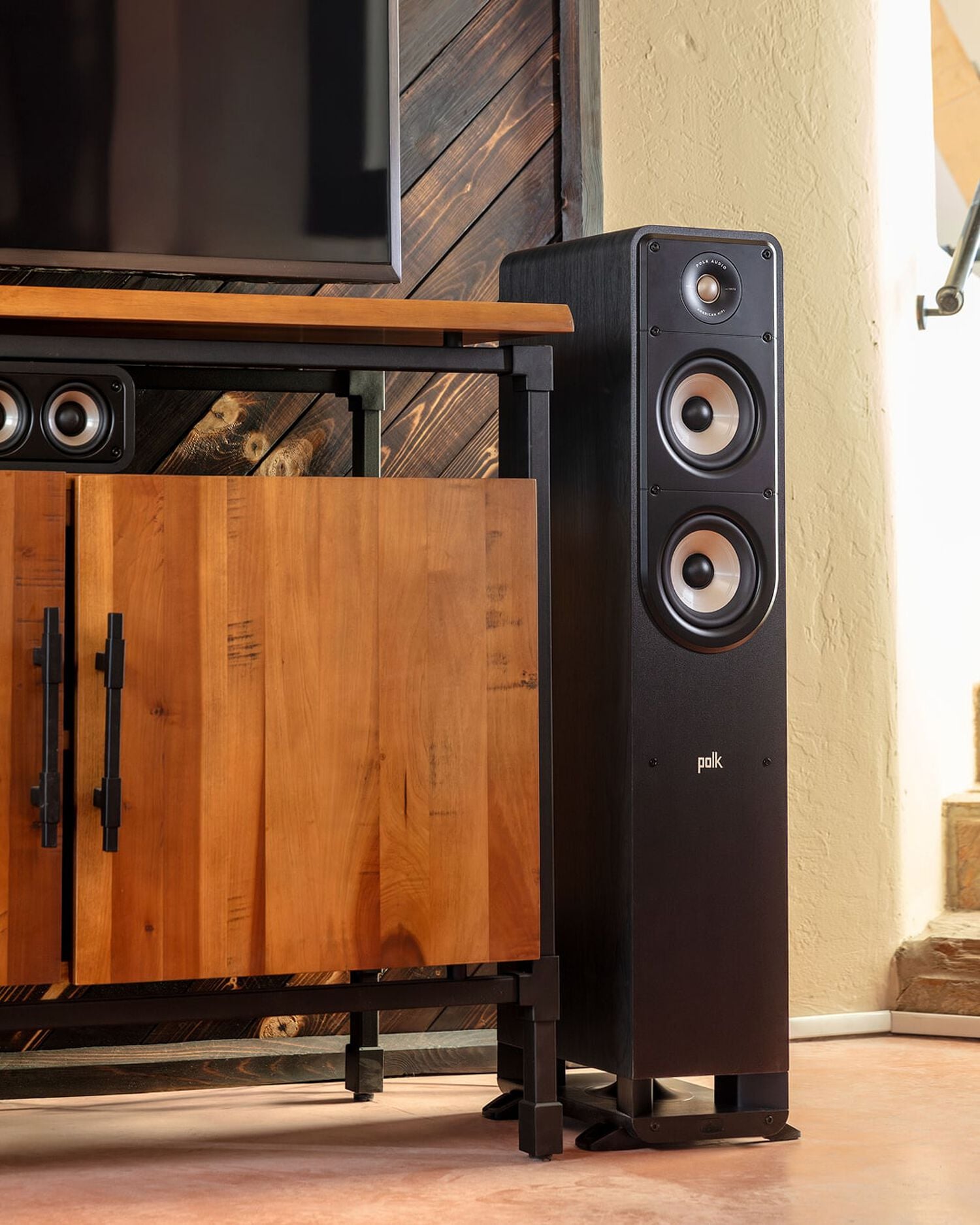 a tower speaker next to a tv stand